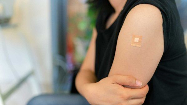 A woman with a bandaid on her arm after receiving a vaccine shot.