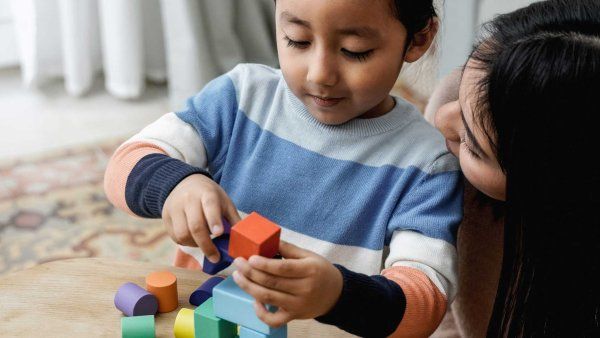 A Latino child and mother play together with toy blocks.