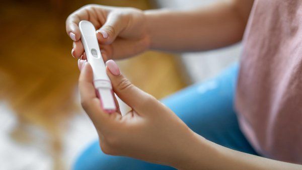 A woman's hands hold a positive pregnancy test.