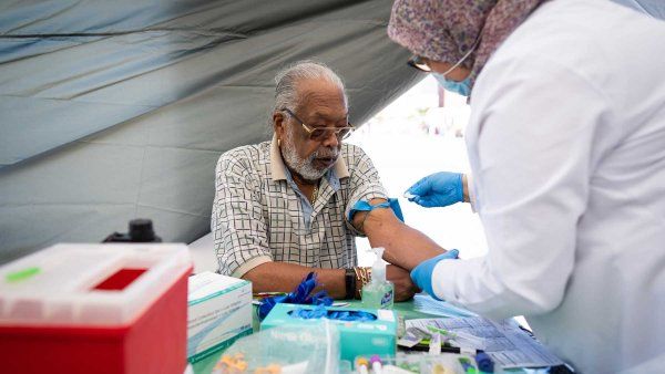 An elderly Black man named Ray Fisher gets a prostate specific antigen test administered by a health practicioner.