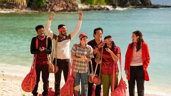 Kishan Patel raises his arms and laughs with several of his fellow reality show contestants on a pristine beach.