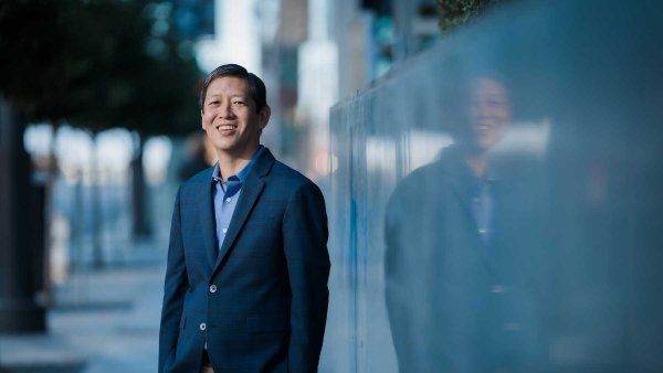 Felix Feng poses for a portrait outdoors among a concrete backdrop.