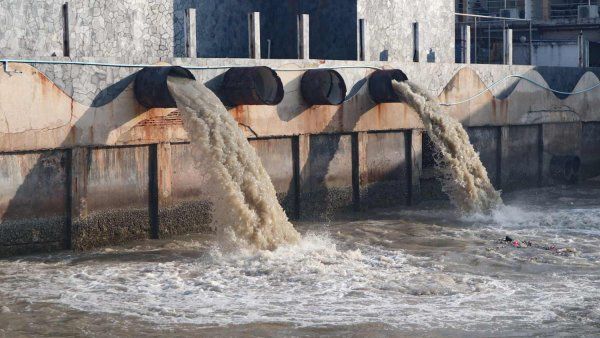 Contaminated water pours out of large drainage pipes.