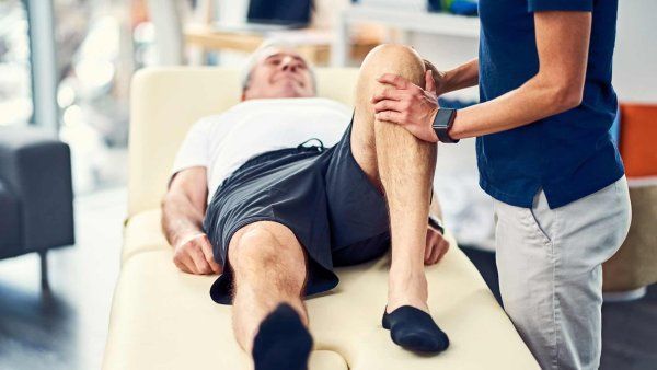 A physical therapist works with an elderly man.