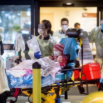 A young patient gets wheeled on a cart from an ambulance through the doors of an emergency room.