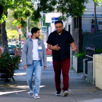 Manuel Tapia walks down the street as he converses with someone in the Mission.