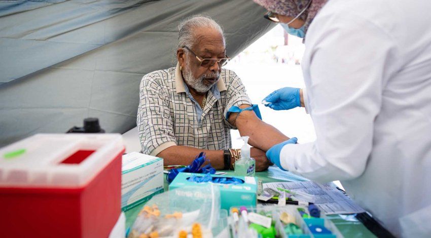 An elderly Black man named Ray Fisher gets a prostate specific antigen test administered by a health practicioner.