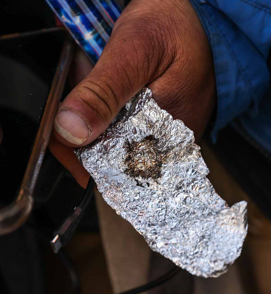A hand holds a piece of foil with fentanyl residue.