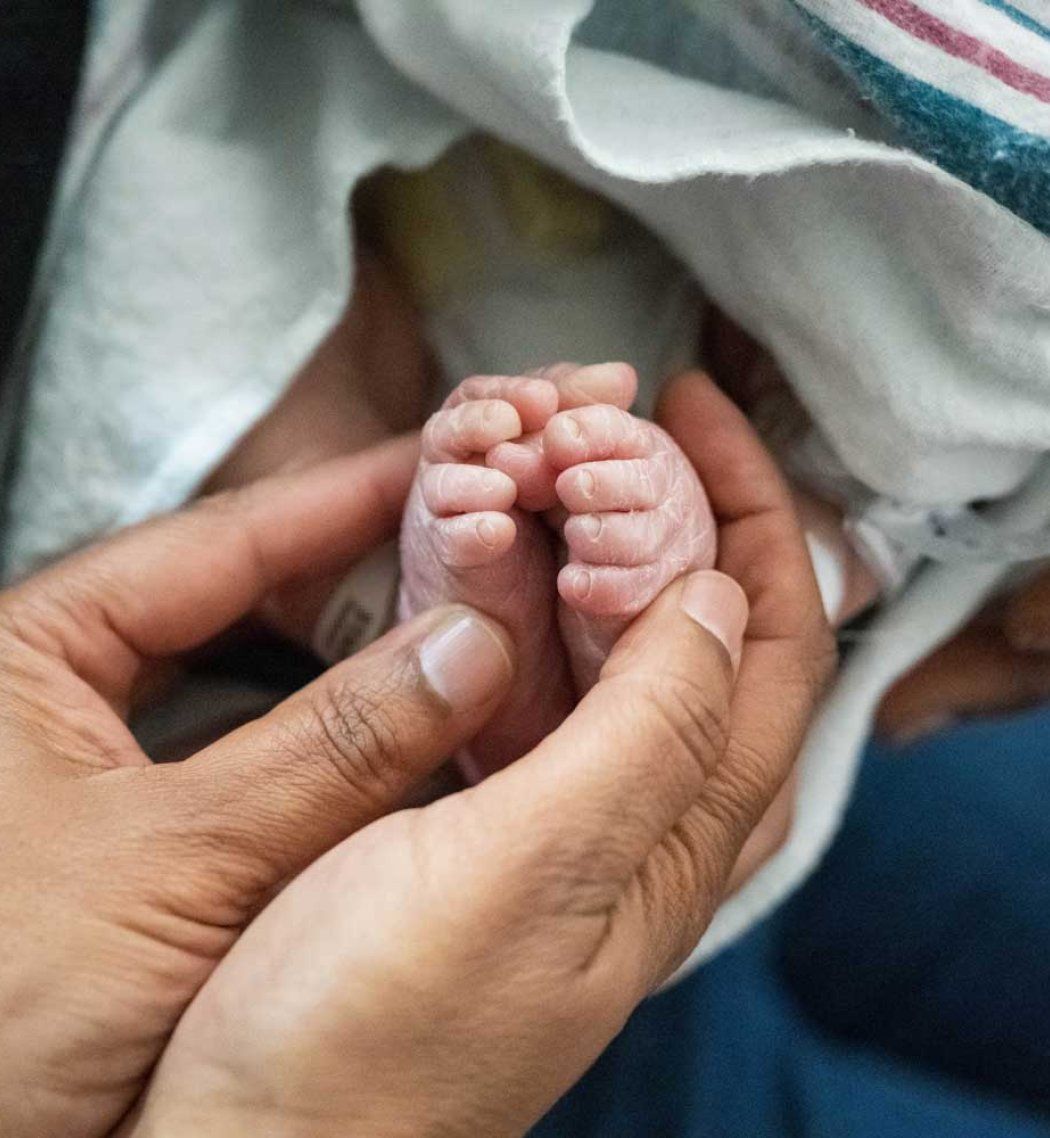 A parent's hands hold a baby's feet.