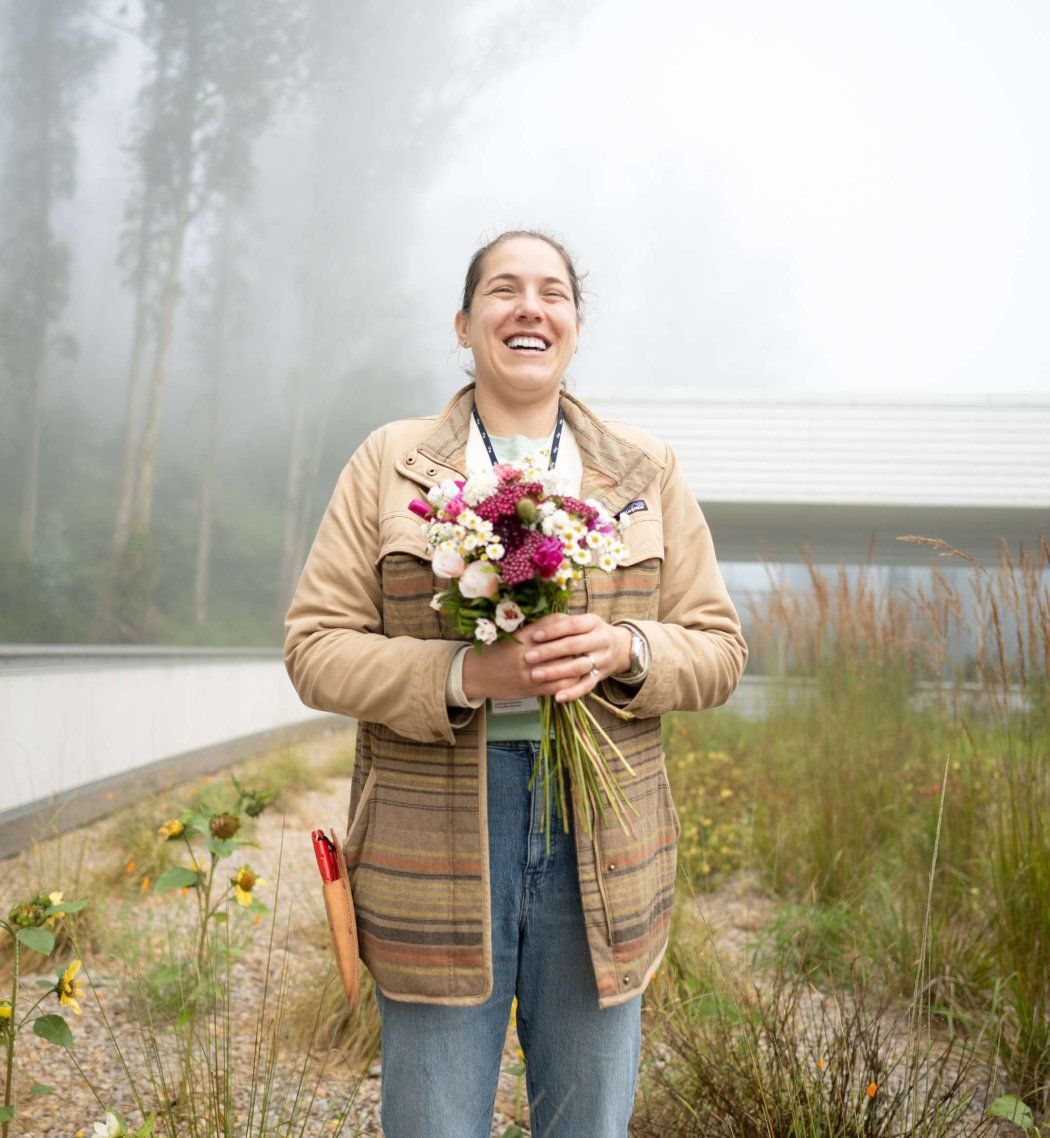 Dunja Duranovic smiles holding fresh wildflower bouquet in hands.