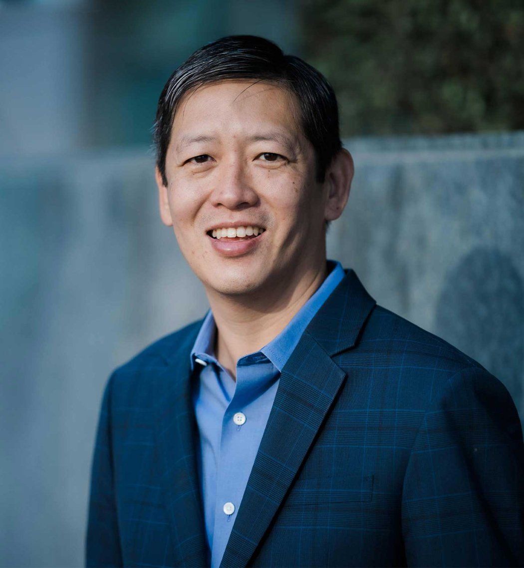 A portrait of Felix Feng, where he stands outside amongst a concrete background.