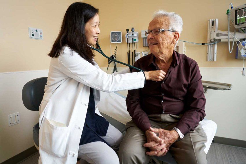 Amy Lin, MD, uses a stethoscope to examine an elderly patient.