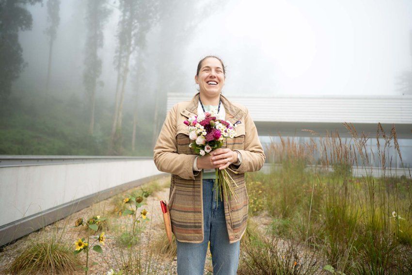 On a foggy day a woman stands on the rooftop holding a bouquet of native wildflowers.