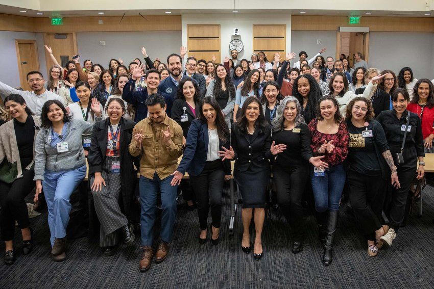 A huge crowd of people cheers with California's surgeon general after her speech.